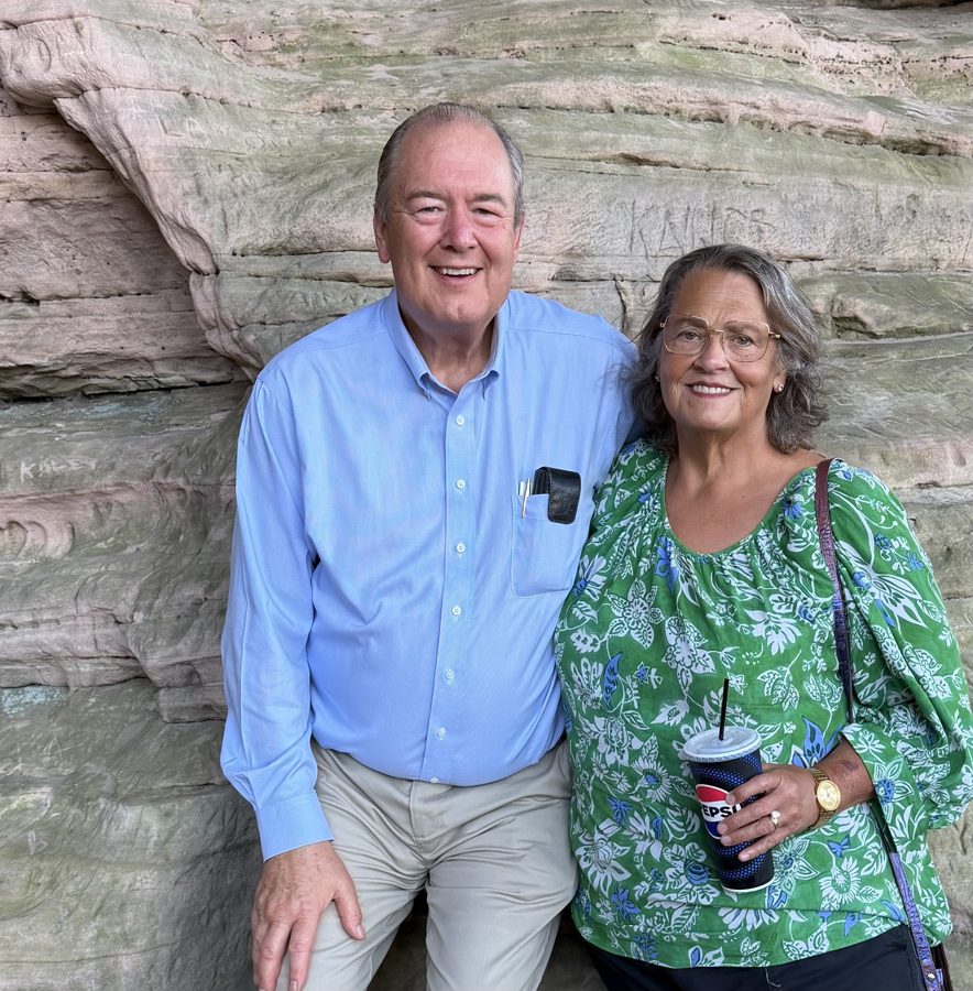 Kathy and Tom Potts smiling together in front of a sandstone rock wall